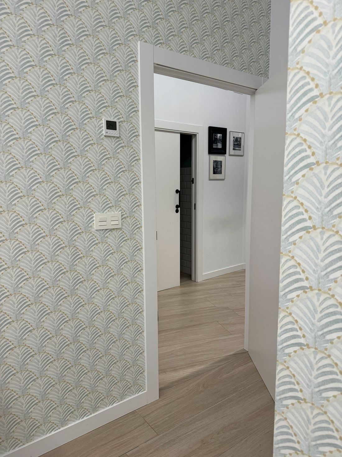 Puerta abierta en sala de espera con vistas al pasillo con pared emmpapelada en tono verdoso como el logotipo